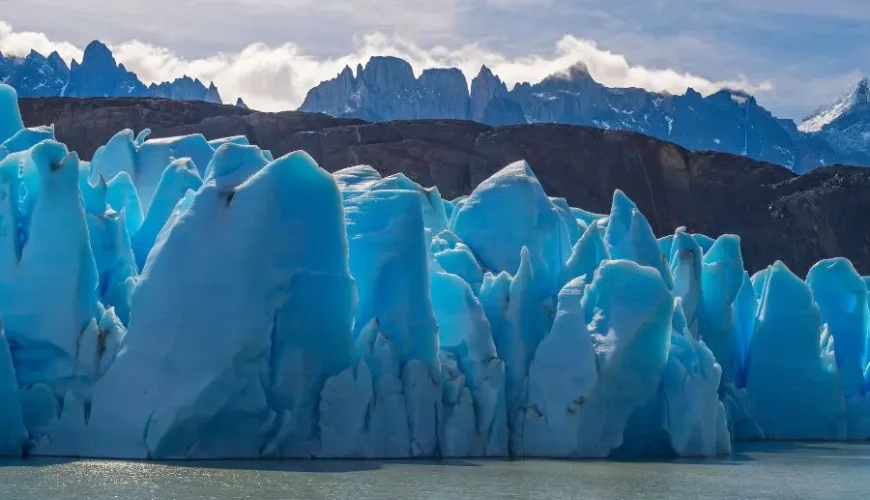 Maestosità glaciale: Il Ghiacciaio Grigio si estende maestoso tra le montagne e il cielo, una meraviglia naturale unica nella Patagonia cilena.