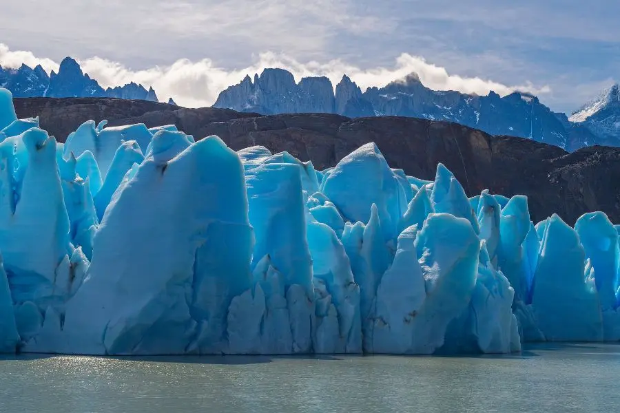 Maestosità glaciale: Il Ghiacciaio Grigio si estende maestoso tra le montagne e il cielo, una meraviglia naturale unica nella Patagonia cilena.