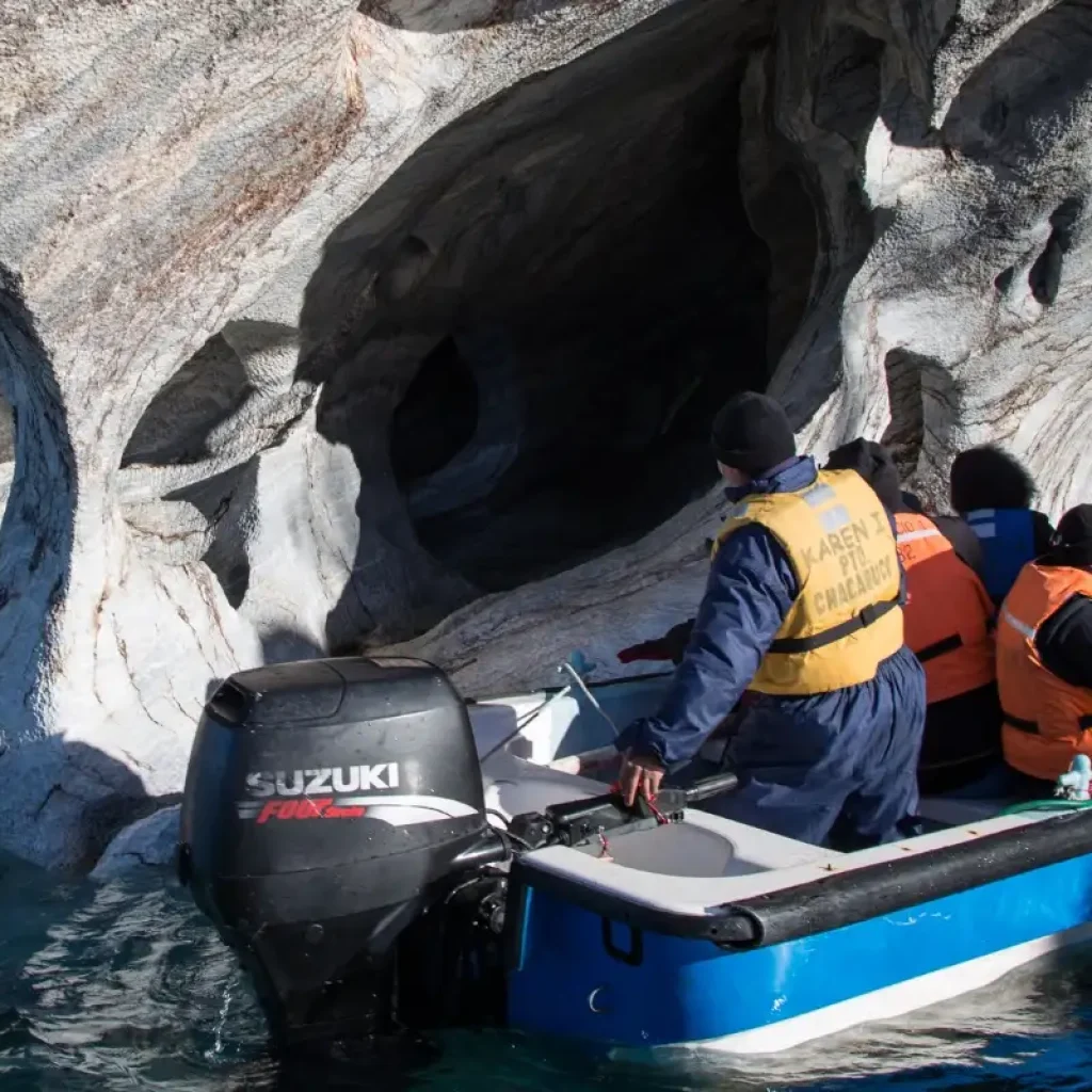 A boat carrying curious travelers explores the intricate beauty of the Marble Caves in Patagonia.