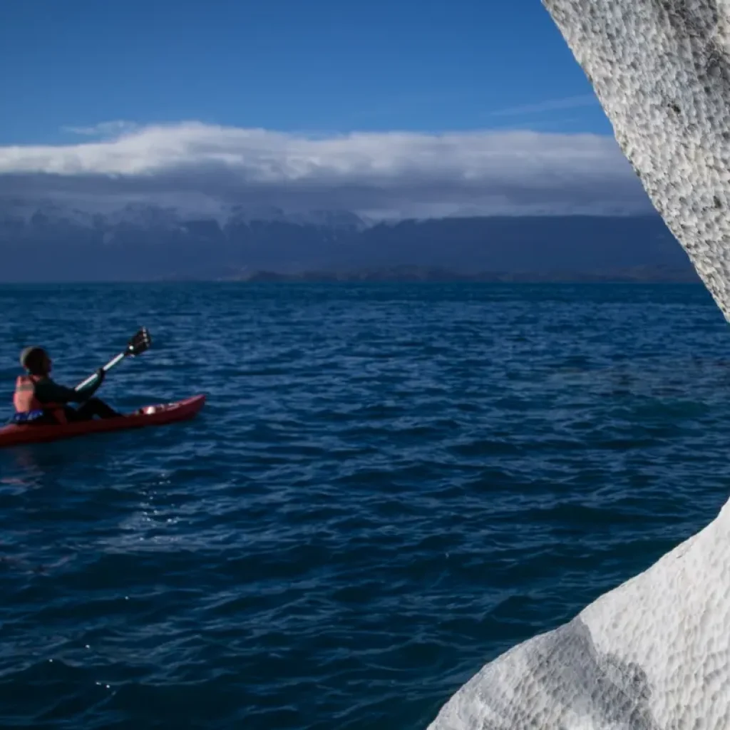 A kayaker glides through the serene turquoise waters of the Marble Caves, surrounded by nature's artistry.