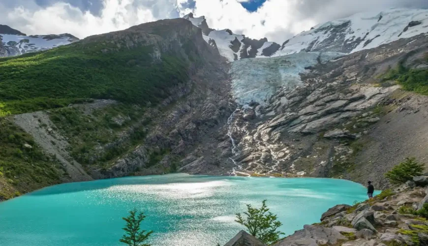 A visitor takes in the serene beauty of Huemul Lake.