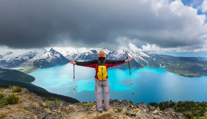 Un escursionista abbraccia la vasta bellezza del ghiacciaio e del lago Garibaldi da un punto di osservazione perfetto.