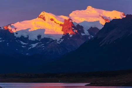 Le coucher de soleil illumine les pics enneigés du parc national de Patagonie de nuances vibrantes d'orange et de rose.