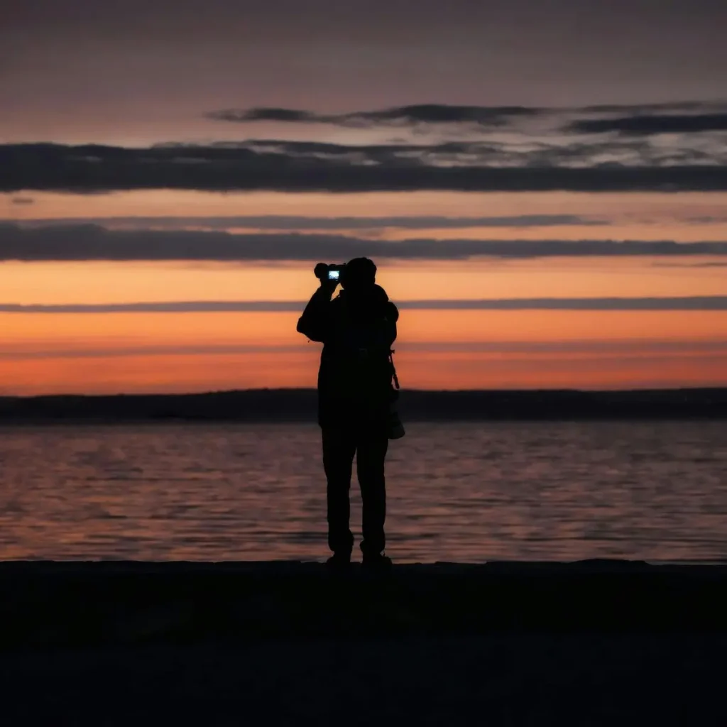Wildtierbeobachter mit Fernglas bei Sonnenuntergang an der patagonischen Küste