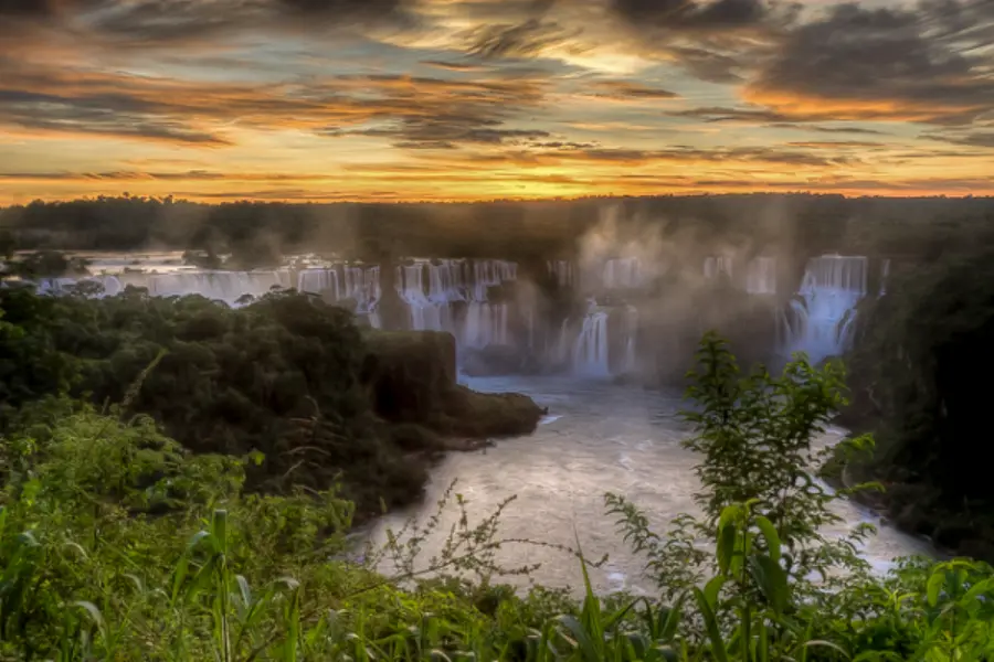 De Iguazú-watervallen bij zonsopgang, met mist die opstijgt boven het oerwoud