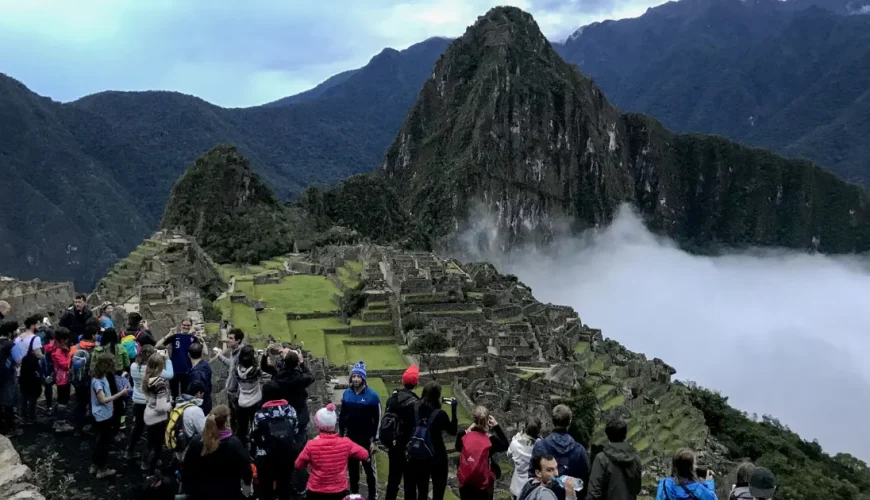 Visitatori che fotografano la cittadella di Machu Picchu e Huayna Picchu sotto una coltre di nuvole basse