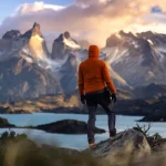 Excursionista con chaqueta naranja frente a los Cuernos del Paine, sobre un lago de color turquesa, en las Torres del Paine, en la Patagonia chilena