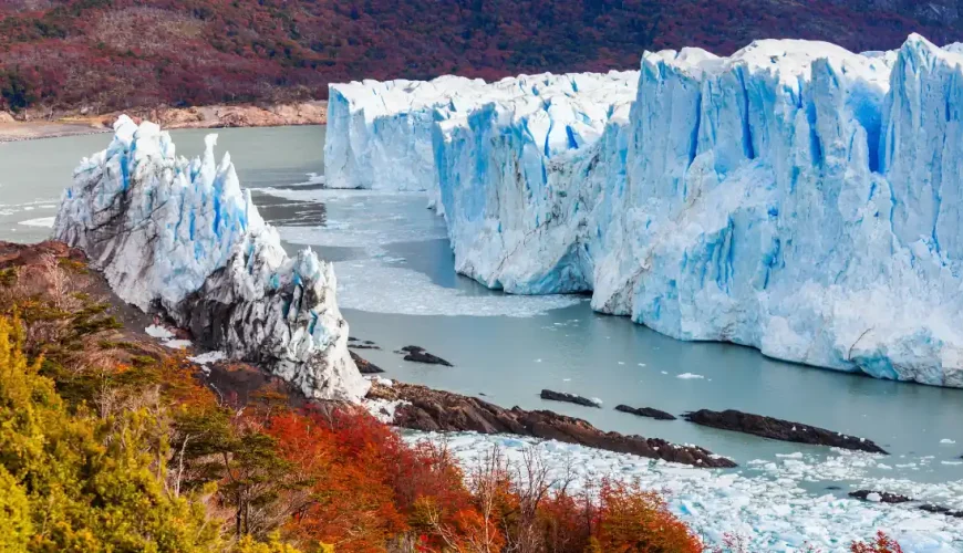 Parete di ghiaccio del ghiacciaio Perito Moreno sopra il Lago Argentino con bosco autunnale, El Calafate, Santa Cruz, Patagonia argentina