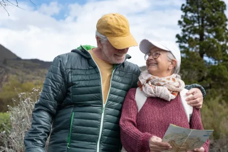 Smiling senior couple holding a trail map on a walk in the hills