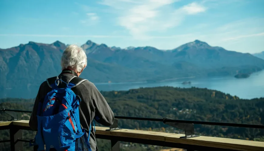Een oudere reiziger met een rugzak bij een uitkijkpunt aan een meer in de Andes, Patagonië, Argentinië